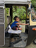 boy at the wheel of a tuk tuk in India