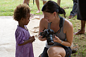 Young woman showing pictures on her camera to fijian child, Naidi, Vanua Levu, Fiji Islands, South Pacific, Oceania