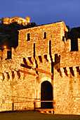 Illuminated draw bridge of castle Castello di Montebello with castle Castello di Sasso Corbaro in background in UNESCO World Heritage Site Bellinzona, Bellinzona, Ticino, Switzerland