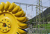 Turbine wheel with relay station in the background, Pelton turbine, water power plant near Loebbia, Bergell range, Grisons, Switzerland