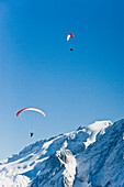 Paraglider über schneebedeckten Dolomiten, Südtirol, Italien