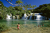 People bathing at Krka waterfalls under blue sky, Krka National Park, Croatian Adriatic Sea, Dalmatia, Croatia, Europe