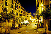 Ein Paar sitzt auf einer Bank vor beleuchteten Restaurants, Vernazza, Cinque Terre, Ligurien, Italienische Riviera, Italien, Europa