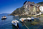 Schlauchboot und Fischerboote im Hafen unter blauem Himmel, Riomaggiore, Cinque Terre, Ligurien, Italienische Riviera, Italien, Europa