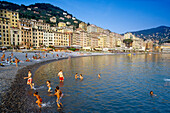 Badende Kinder am Strand unter blauem Himmel, Camogli, Italienische Riviera, Ligurien, Italien, Europa