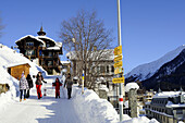 Skiers carrying skies along snowy path, Davos, Grisons, Switzerland