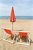 Two red deck chairs and a sunshade on the beach, sea, Castellabate, Cilento, Italy