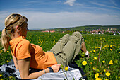 Frau sitzt mitten in der Wiese, Wanderung bei Tabarz, Nahe Eisenach, Thüringen, Deutschland