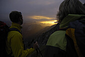 Bergwanderer beobachten Sonnenuntergang von der Klammspitze, Bayern, Deutschland