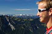Gesicht eines Wanderers und Aussicht auf Gebirge im Sonnenlicht, Wendelstein, Bayern, Deutschland, Europa