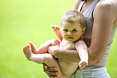 Mother holding baby on meadow, 9 month