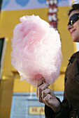 Mid adult woman with pink cotton candy, Prater, Vienna, Austria