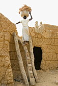 Burkina Faso. Sahel. Lobí Country. Sukala traditional house. Animist Village. Women carrying millet.