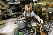 middle aged woman cooking in a busy restaurant kitchen