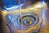 Running water drained off by the drain of a kitchen. A mixture of light and warm to cold exposure.