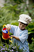 Toddler is watering plants in the garden