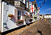 Street Scene with flags and flowers on harbourside buildings, Dartmouth, Devon, UK, England