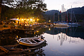 Menschen auf der Terrasse eines Restaurants in einer Bucht mit Anlegestelle, Kapi Creek, Fethiye Bucht, Türkei, Europa