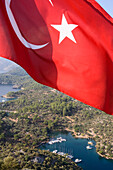 Die türkische Flagge und Blick auf die kleine Bucht Kapi Creek, Fethiye Bucht, Türkei, Europa