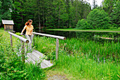 Woman standing on small bridge, Bavarian Forest National Park, Lower Bavaria, Bavaria, Germany