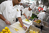 Galley on board a cruise ship, Cooks in the kitching preparing vegetables, Cruise liner Queen Mary 2