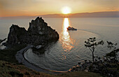 Boat near Shaman Rock at Cape Burchon on Olchon Island at sunset, Lake Baikal, Russian Federation