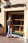 Girl window shopping outside luxury shop, Porto Cervo, Sardinia, Italy