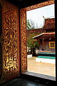 Wat Xieng Thong, view through richly painted window, Luang Prabang, Laos