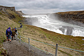 Tourists walking beside waterfall, Gulfoss, Iceland