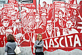 Junge Frauen stehen vor einer Wandmalerei, Orgosolo, Sardinien, Italien, Europa