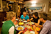 People sitting laughing at a table at a fish restaurant, Posada, Sardinia, Italy, Europe