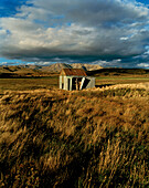 Pasture with little hut under clouded sky, Central Otago, South Island, New Zealand