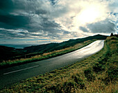 Summit Road mit Blick über Okains Bay unter grauen Wolken, Banks Peninsula, Südinsel, Neuseeland