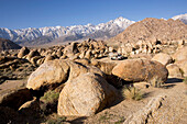 Vie at an American school bus in a rocky desert in front of snow covered mountains, Alabama Hills, Lonepine, California, USA