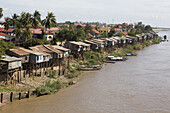 Huts built on stilts at the river Tonle Sap under clouded sky, Phnom Penh, Cambodia, Asia