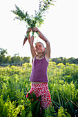Girl (8-9 years) holding carrots up, Lower Saxony, Germany