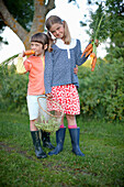 Two girls (6-9 years) with fresh carrots, Lower Saxony, Germany