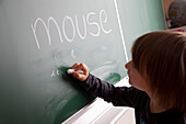 Schoolboy writing on blackboard, Hambug, Germany