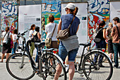 Cyclists And Tourists In Front Of Fragments Of The Berlin Wall, Potsdamer Platz, Berlin, Germany