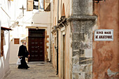 Orthodox Priest In An Alley Near The Haghios Nikolaos Church, Crete, Greece