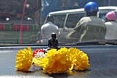 Buddha Surrounded By Flowers On The Dashboard Of A Taxi In The Traffic Of Bangkok, Thailand