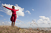 Woman with outstreched arms at beach of Utersum, Foehr island, Schleswig-Holstein, Germany