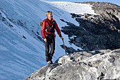 Bergsteiger mit Eispickel steht auf einem Felsen, Clariden, Kanton Uri, Schweiz