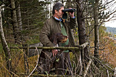 chief forester Menzel, ranger, observes with binoculars and dog in the Sau Park Springe, Hanover region, Lower Saxony, northern Germany