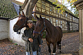 Kuntze-Hof in Schloss Ricklingen, Fachwerkhaus mit Vorgarten, Laubbäume mit bunten Blättern, Pferde am Führstrick, Reiter