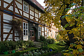 Kuntze-Hof in Schloss Ricklingen, Fachwerkhaus mit Vorgarten, Laubbäume mit bunten Blättern, verzierter Türeingang
