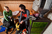 Young woman and mature man packing backpacks in a Saoseo mountain lodge, Puschlav, Grisons, Switzerland