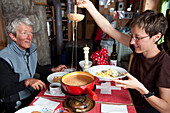 Two women enjoying tomato fondue, mountain lodge Cabane de l'A Neuve, Val Ferret, Canton of Valais, Switzerland