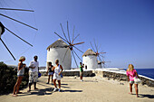 People and windmills at Venetia quarter under blue sky, island of Mykonos, the Cyclades, Greece, Europe