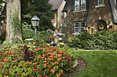 Impatiens in front yard of 1930s brick home with autumn decorations